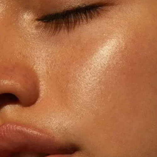 Close-up of glowing, dewy skin with natural makeup and soft lighting.